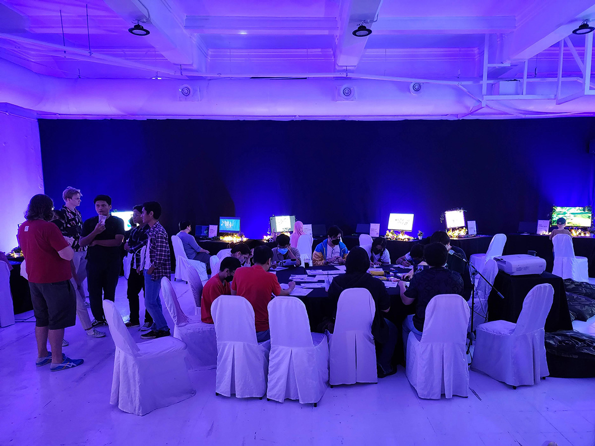 Wide shot of the exhibition space, including workshop table and games in the background.