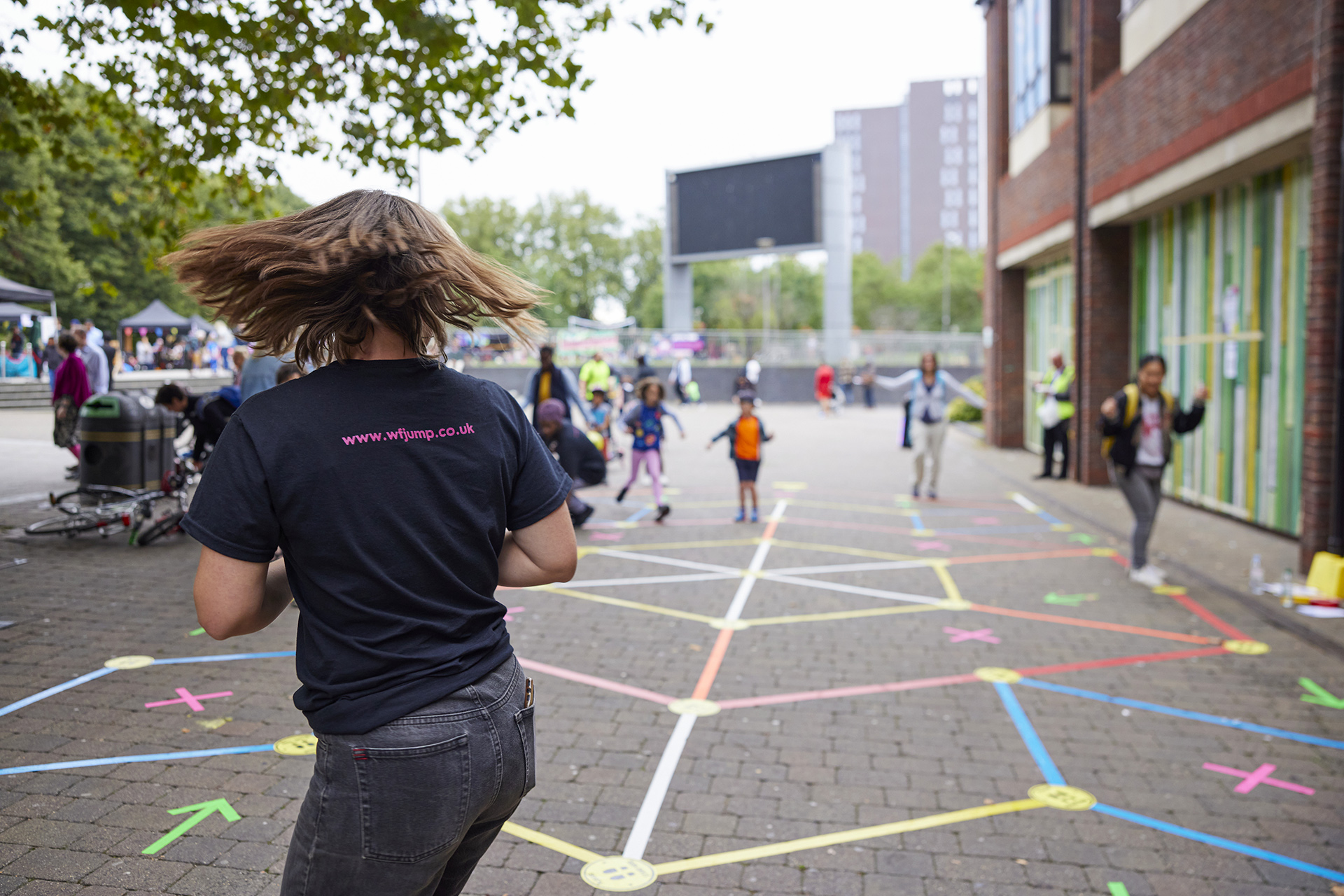 Facilitator turning around to spot players standing on different tapes of the Street Tape Games installation.