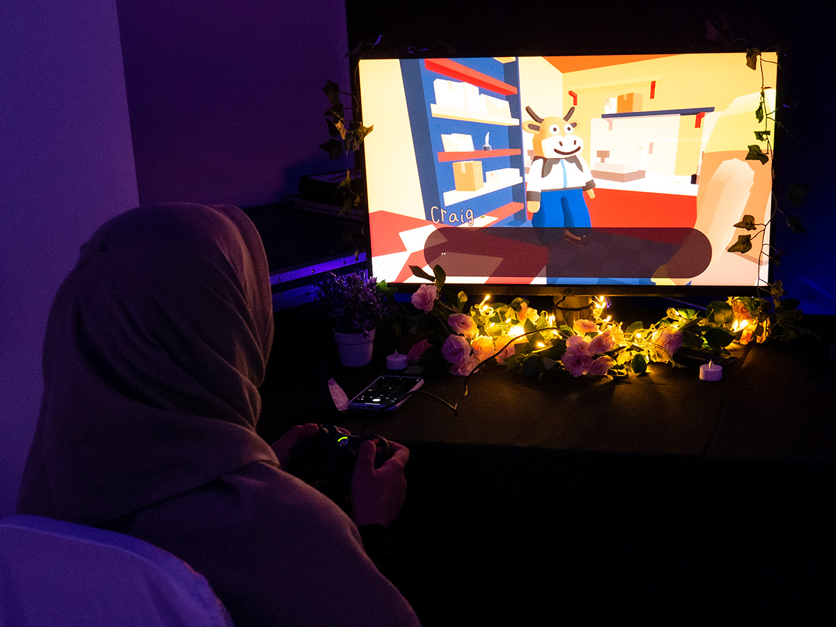 A hijab wearing woman playing Frog Detective 3 at the exhibition.