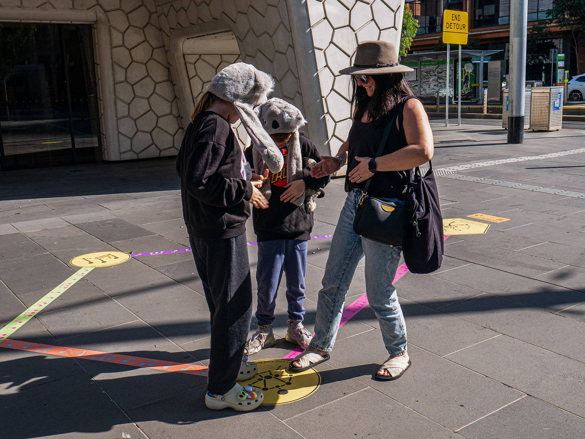 A family drumming their tummies as part of a mini-game from the Rainbow Paths installation at Melbourne Recital Centre.