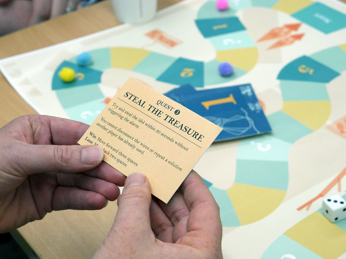 Player reading a Quest Card from the MAGI Board Game.