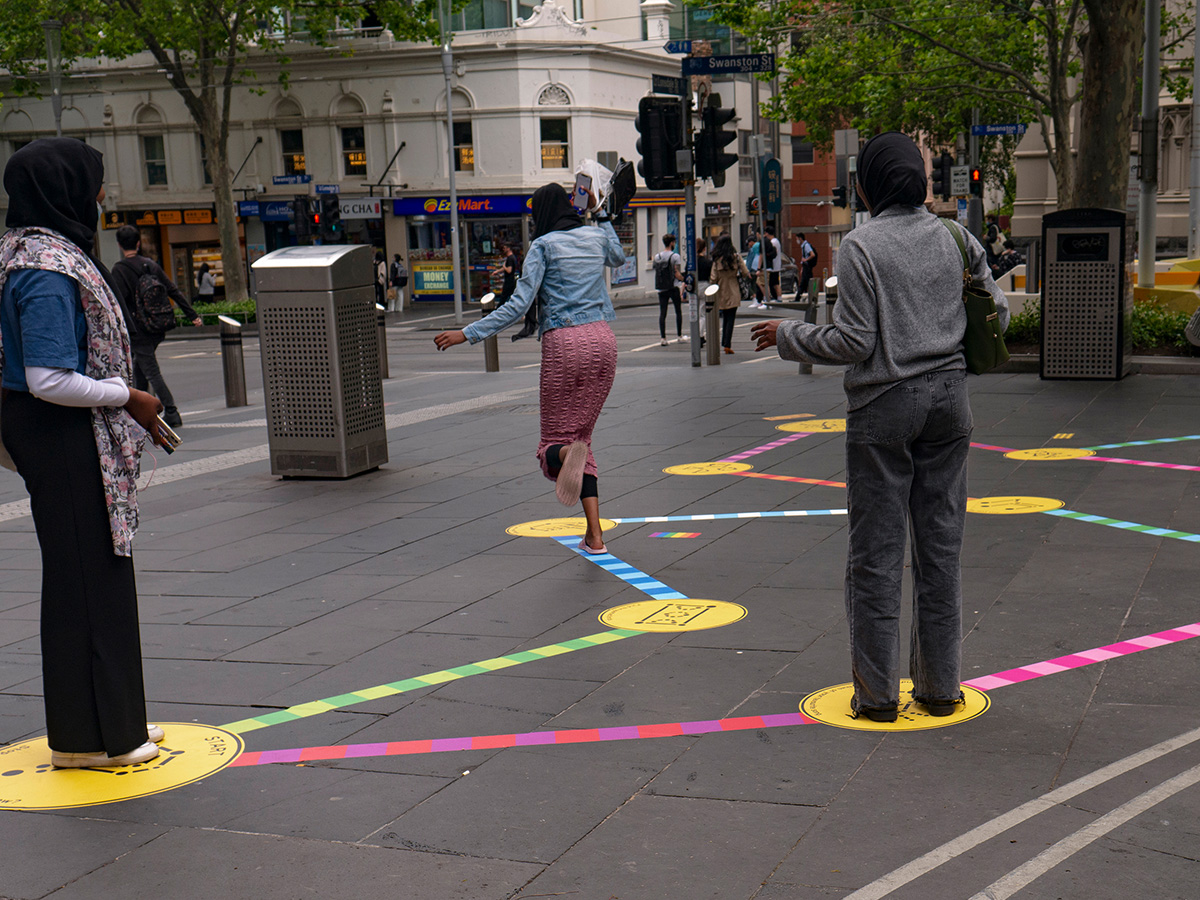 Three hijabi women playing the Rainbow Paths installation at SLV.