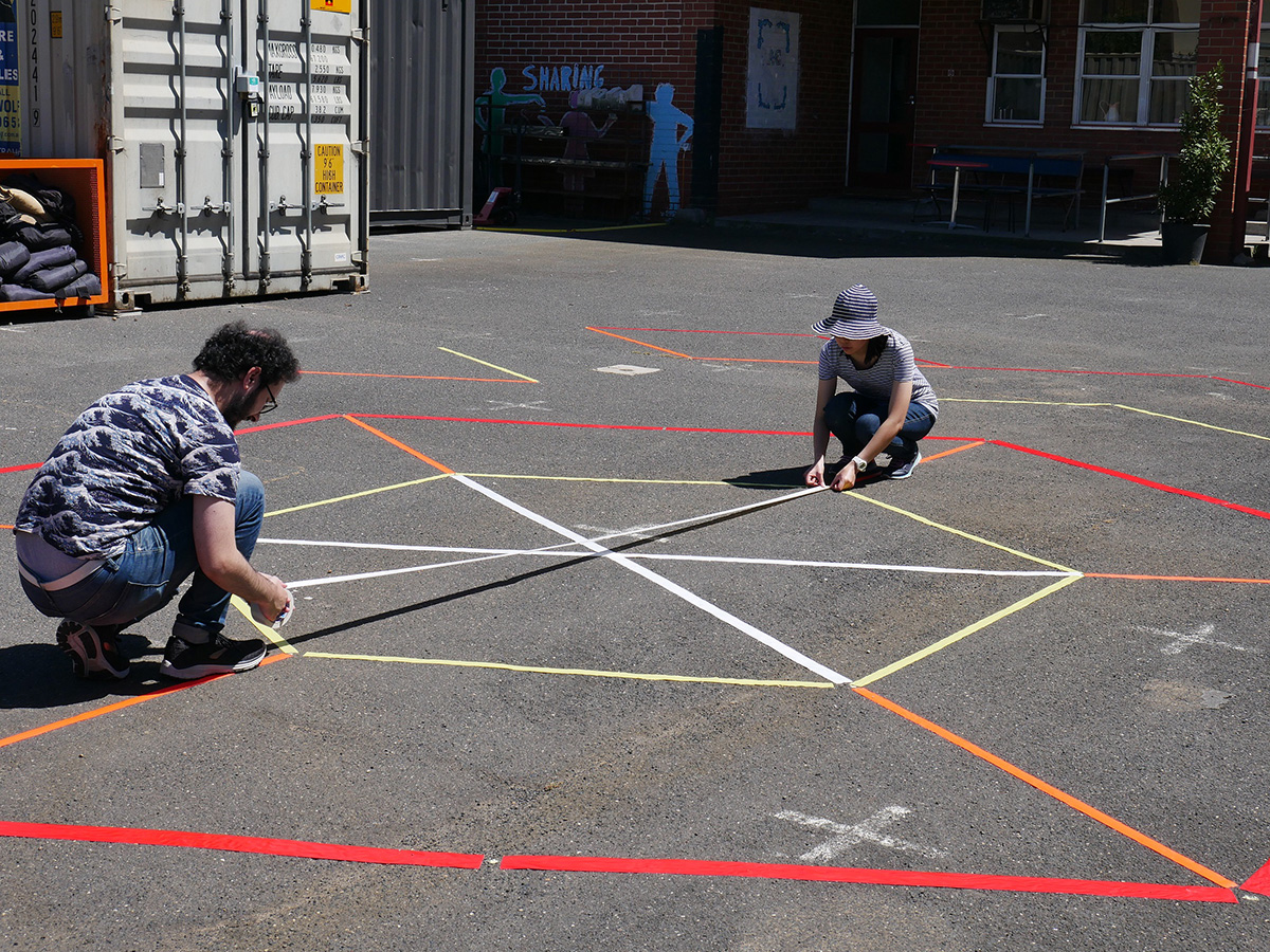 Artists Helen Kwok and Chad Toprak applying tape for the installation.