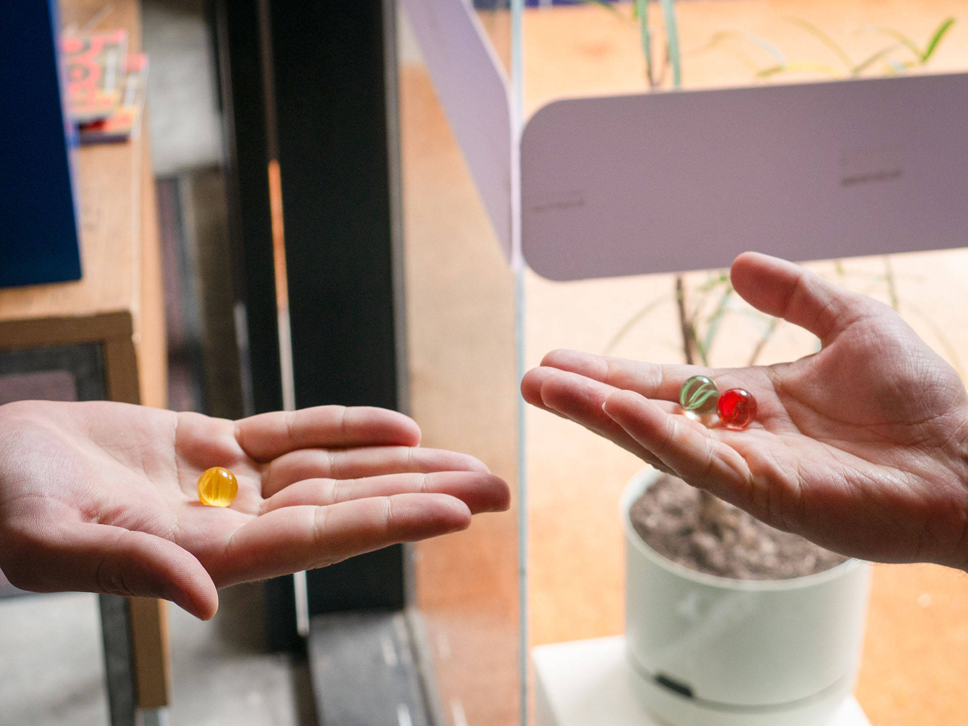 Two hands holding marbles as participants play in the Traces of Play workshop.